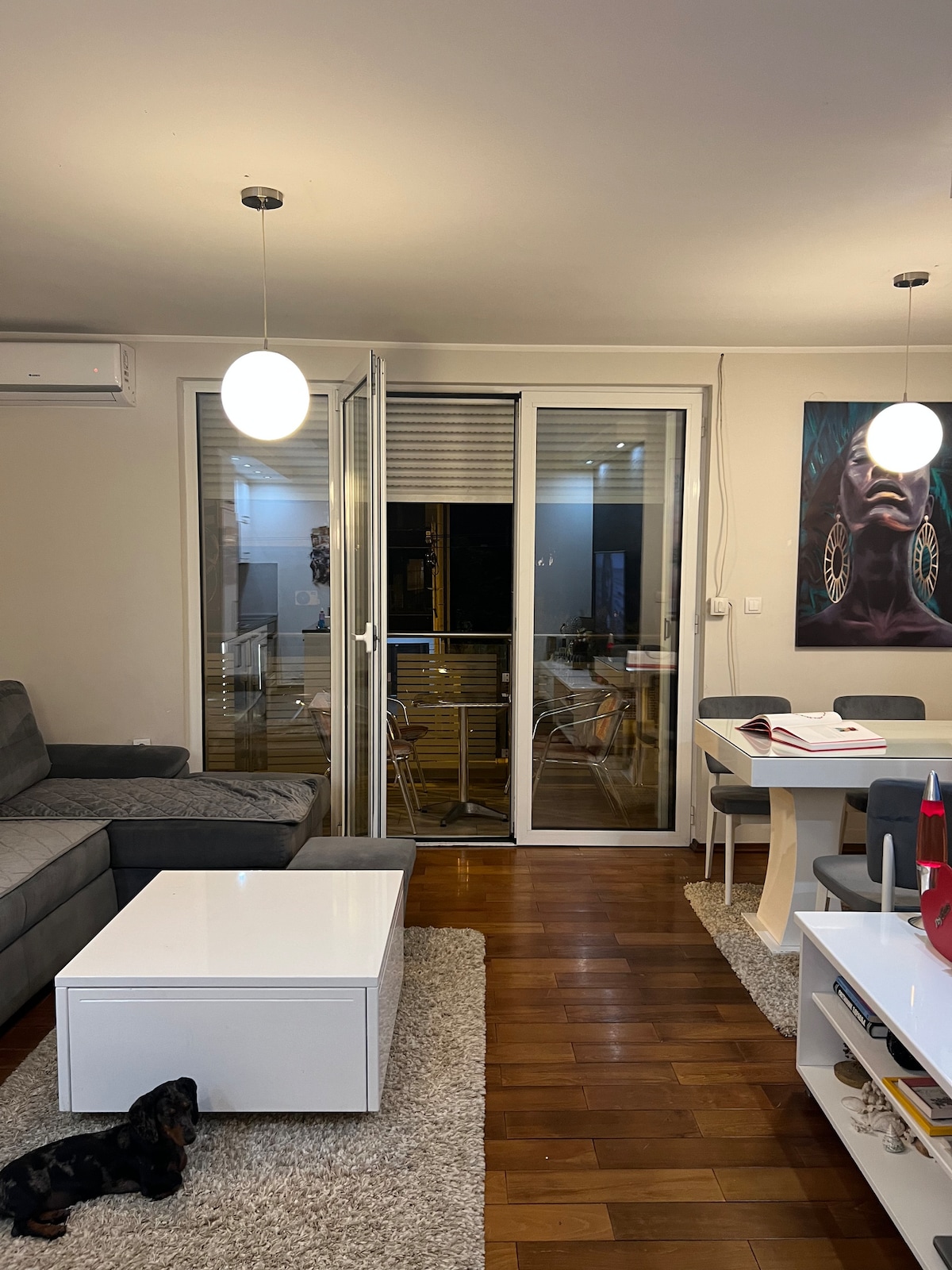 Cosy living room with a grey sectional sofa, statement artwork and a balcony